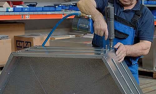 Mitarbeiter bringt Nieten an Baugruppe an